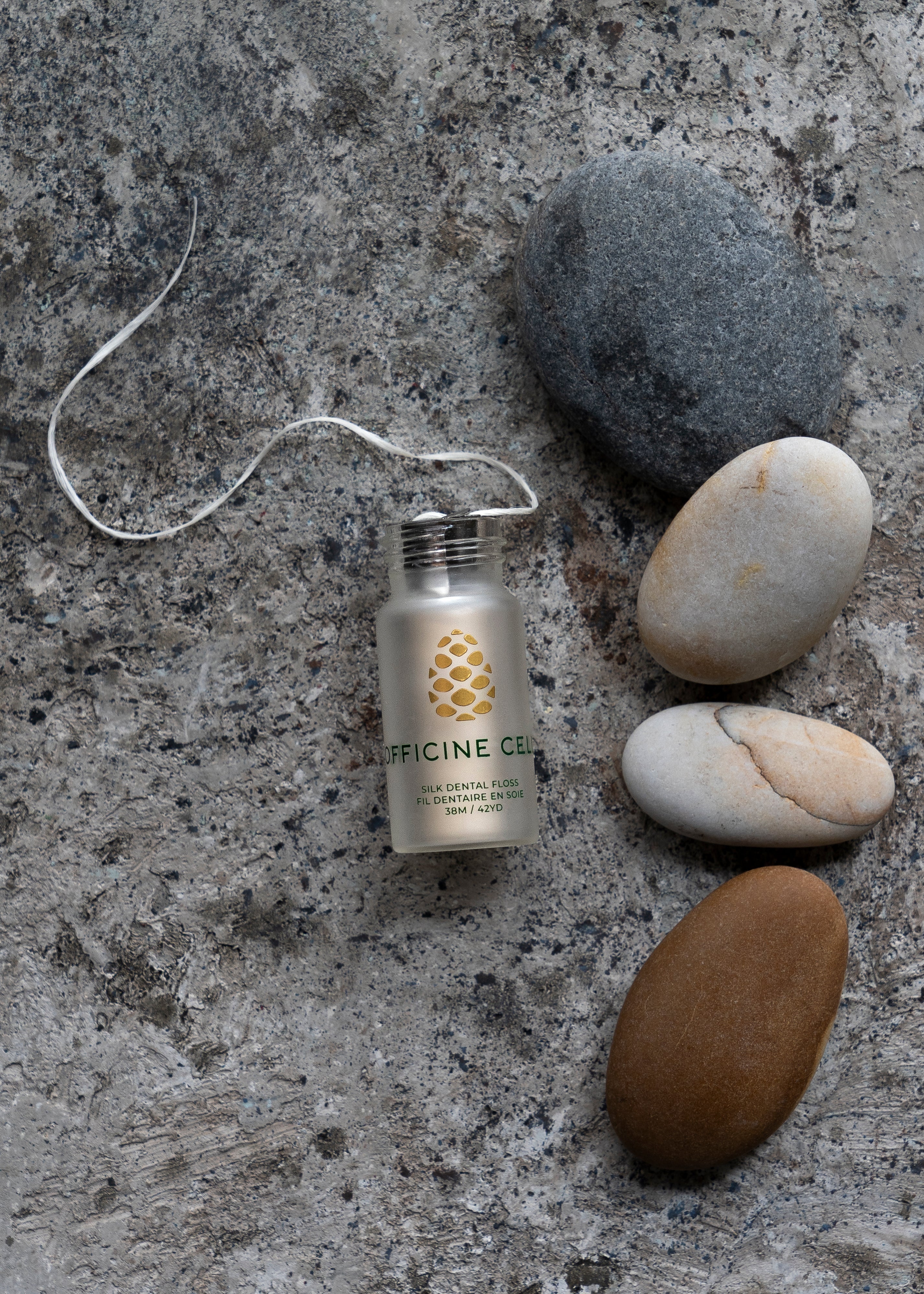 Officine Celli Silk Floss open jar with thread on stone